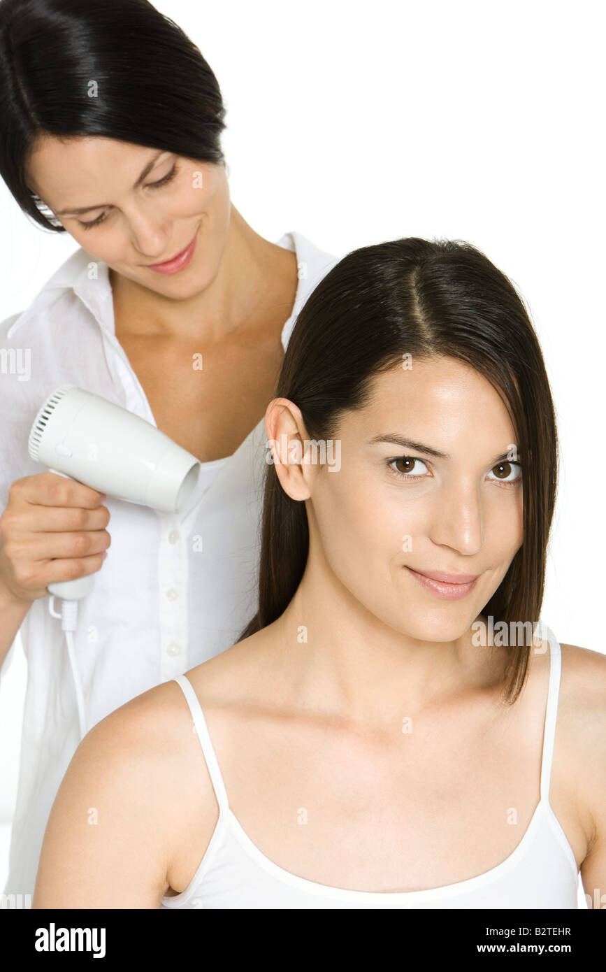 Woman having hair dried by stylist, smiling at camera Stock Photo