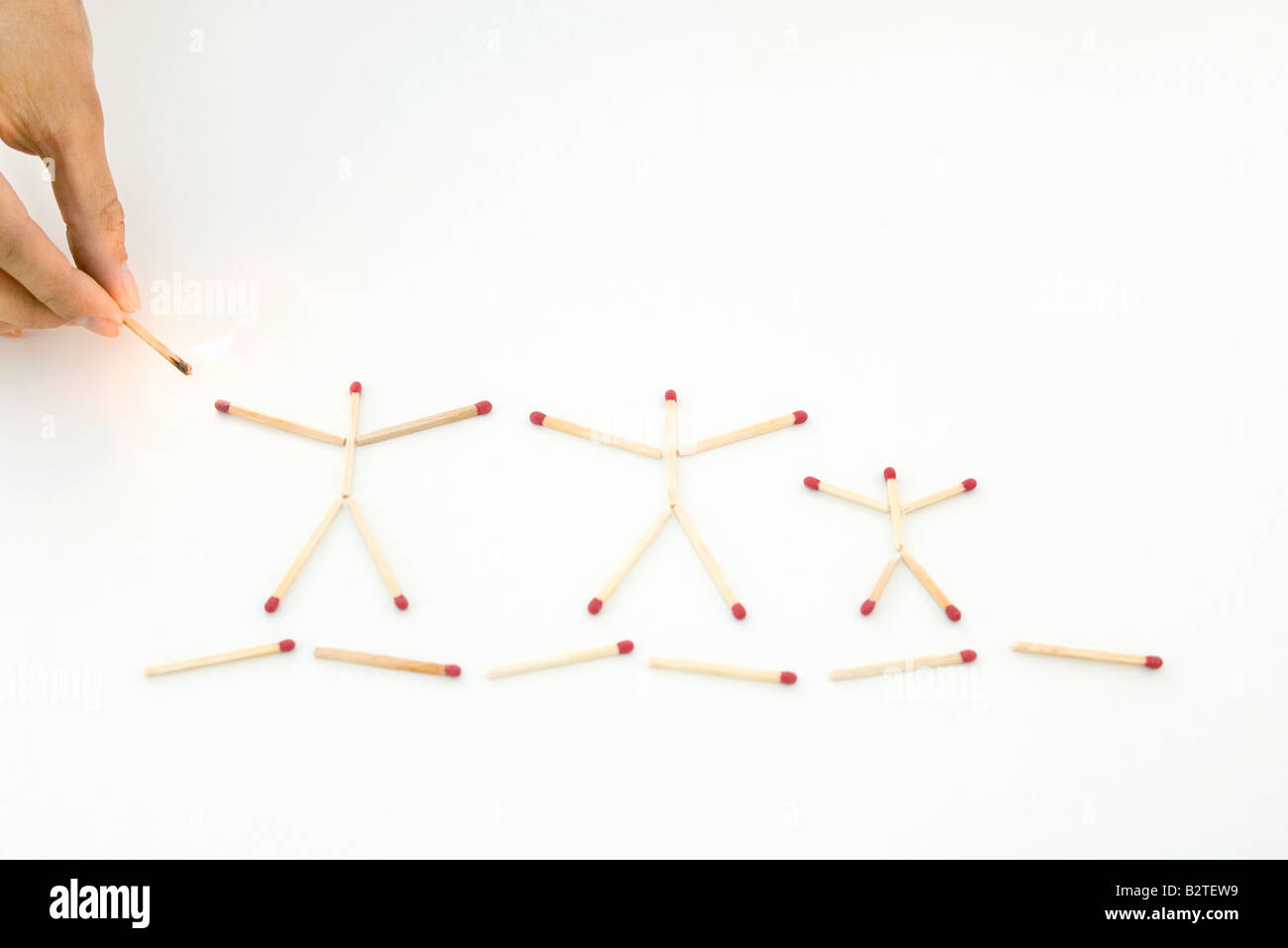 Hand holding lit match up to unlit matches arranged as stick figures Stock Photo Alamy