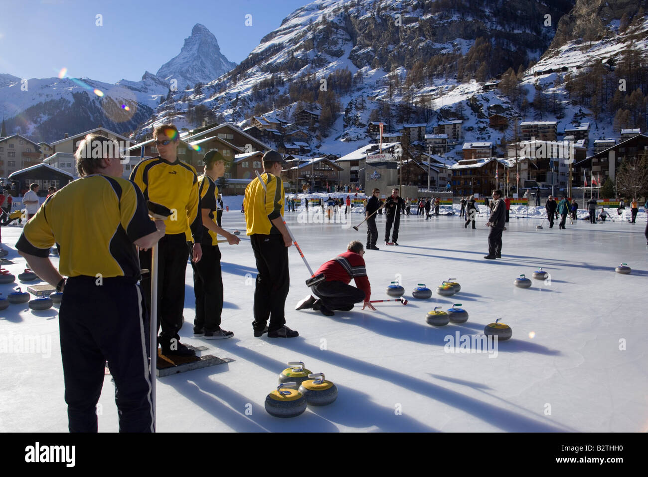 Group of men curling on a rink, Matterhorn in background, Zermatt, Valais, Switzerland (Curling: A rink game where round stones Stock Photo