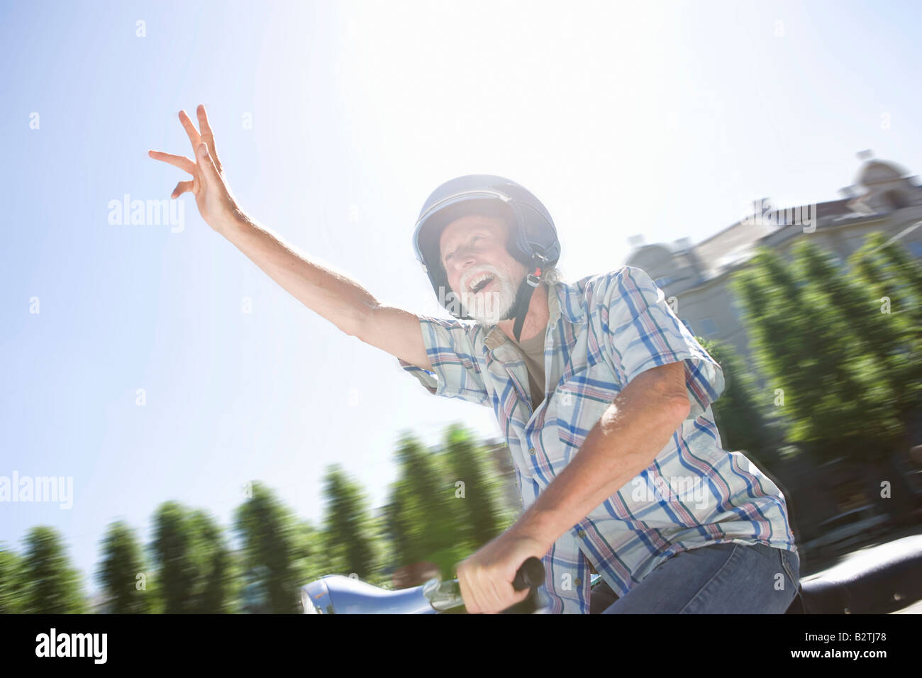 Man on scooter, waving Stock Photo