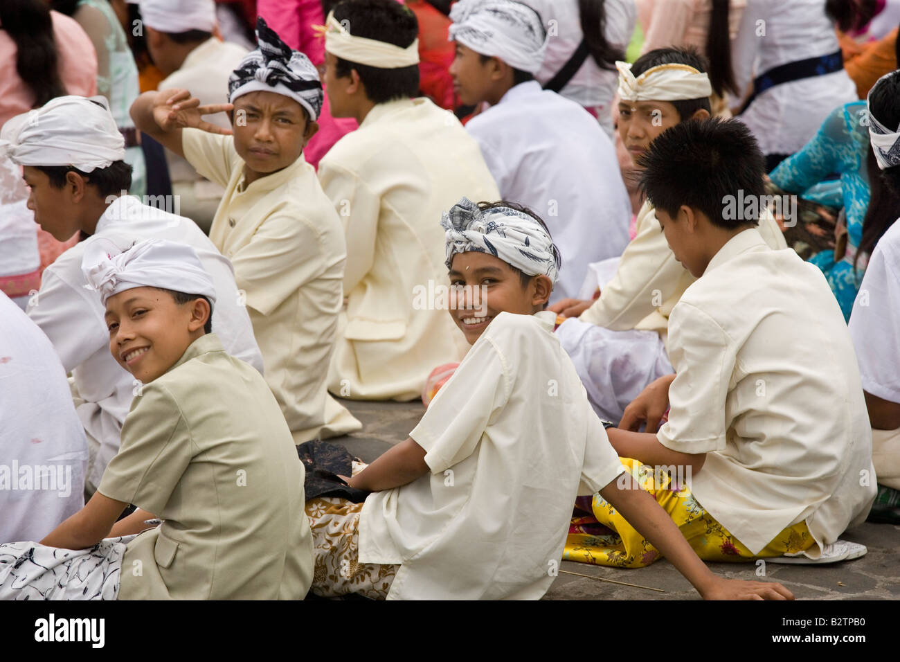 Indonesian boys sitting at Tanah Lot an ancient Hindu temple by the sea in Bali Indonesia Stock Photo