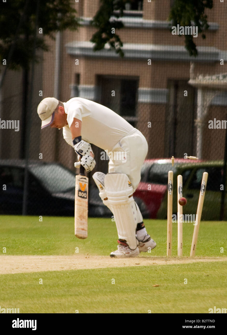 A batsman is cleanly bowled out with the stumps flying from the wicket Stock Photo