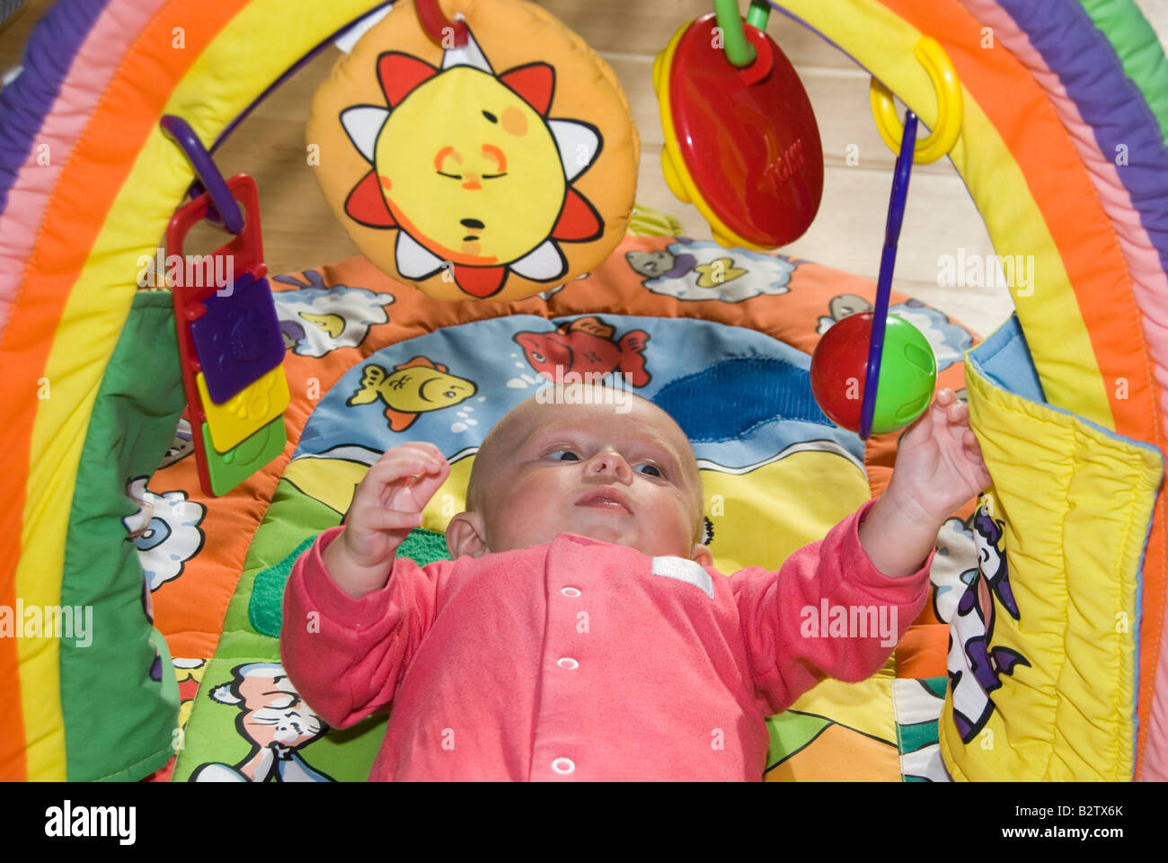 Baby Boy Joshua Kailas Hudson Aged 15 Weeks Playing at Shaking the Hanging Rattle of his Colourful Toy Baby Gym Stock Photo