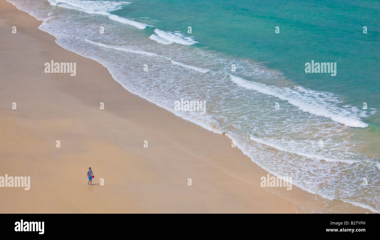 tourist walking on the empty beach at Carbis bay between Hayle and St Ives Cornwall England UK GB EU Europe Stock Photo
