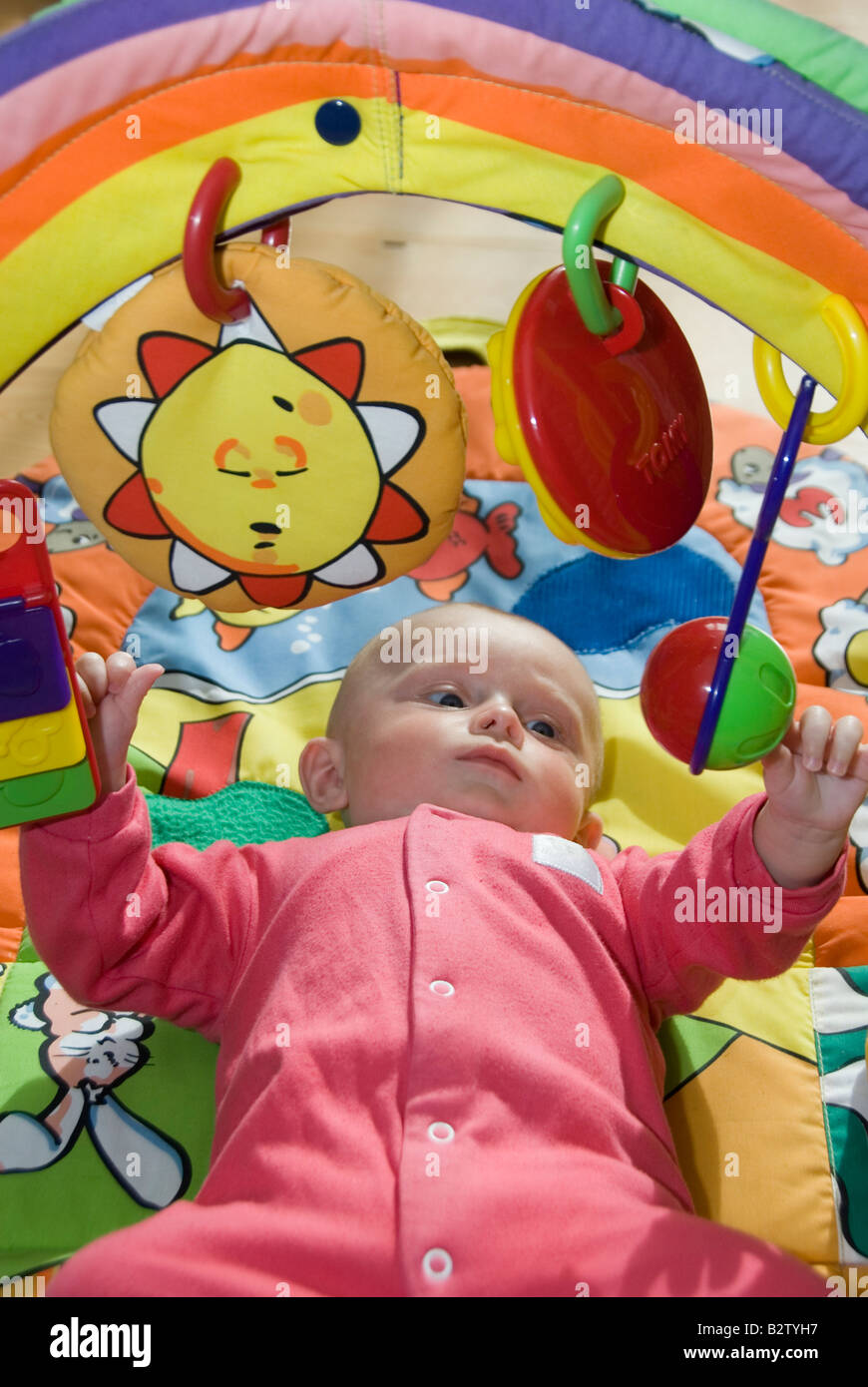 Baby Boy Joshua Kailas Hudson Aged 15 Weeks Playing with Hanging Rattle of his Colourful Toy Baby Gym Stock Photo
