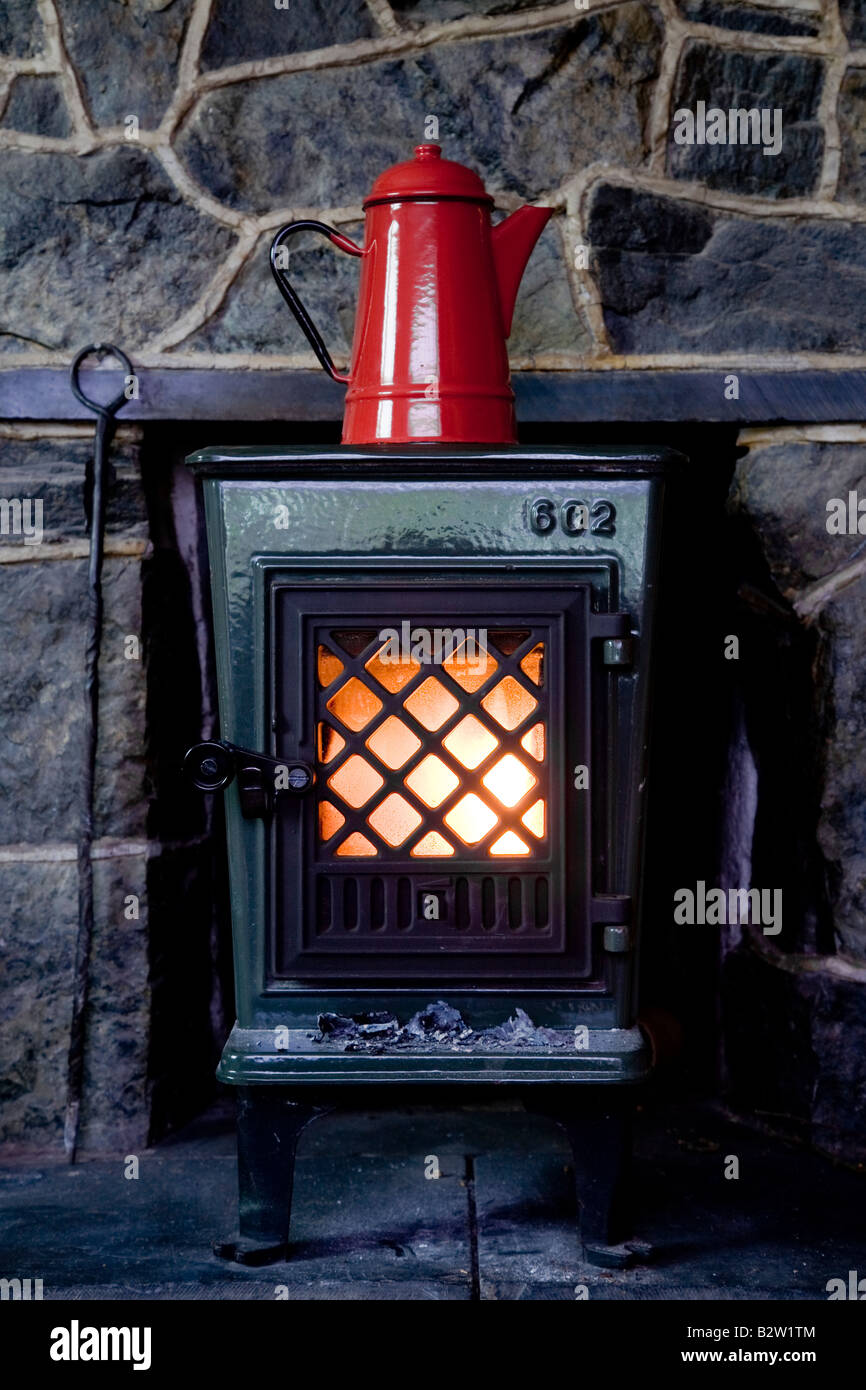 Red kettle sits atop a traditional wood burning stove Stock Photo Alamy
