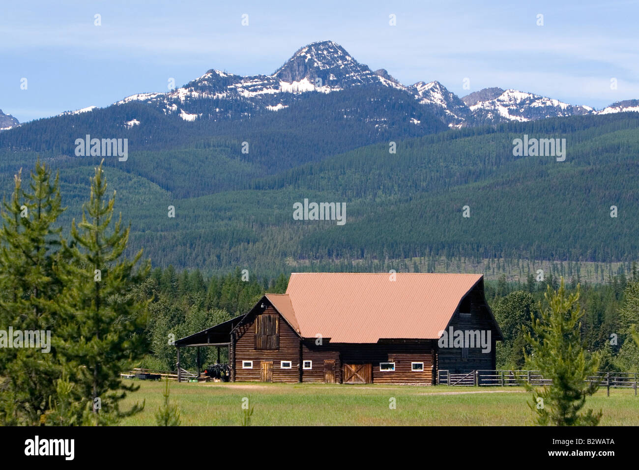 Log barn sits below the Mission Mountains north of Missoula Montana Stock Photo