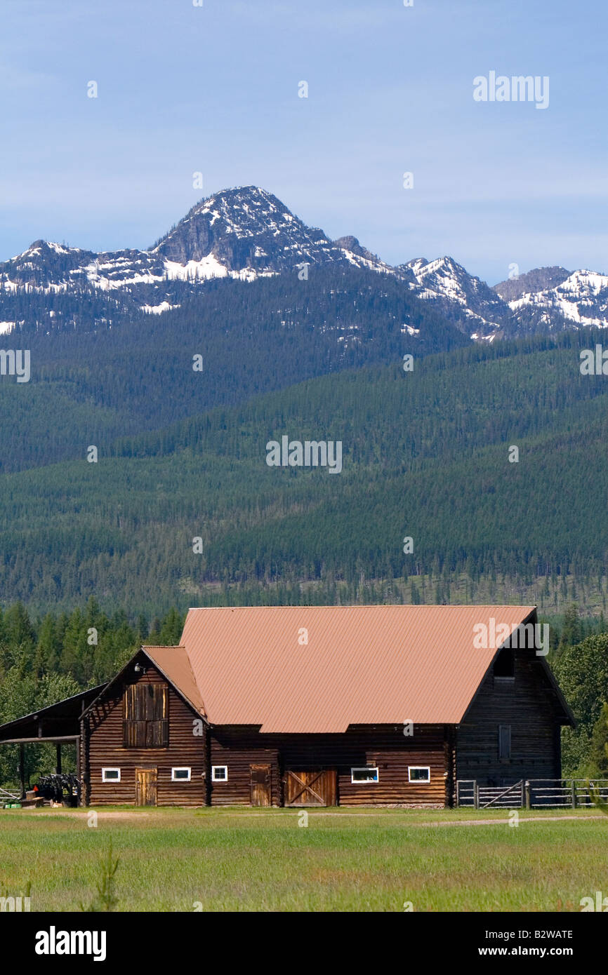 Log barn sits below the Mission Mountains north of Missoula Montana Stock Photo
