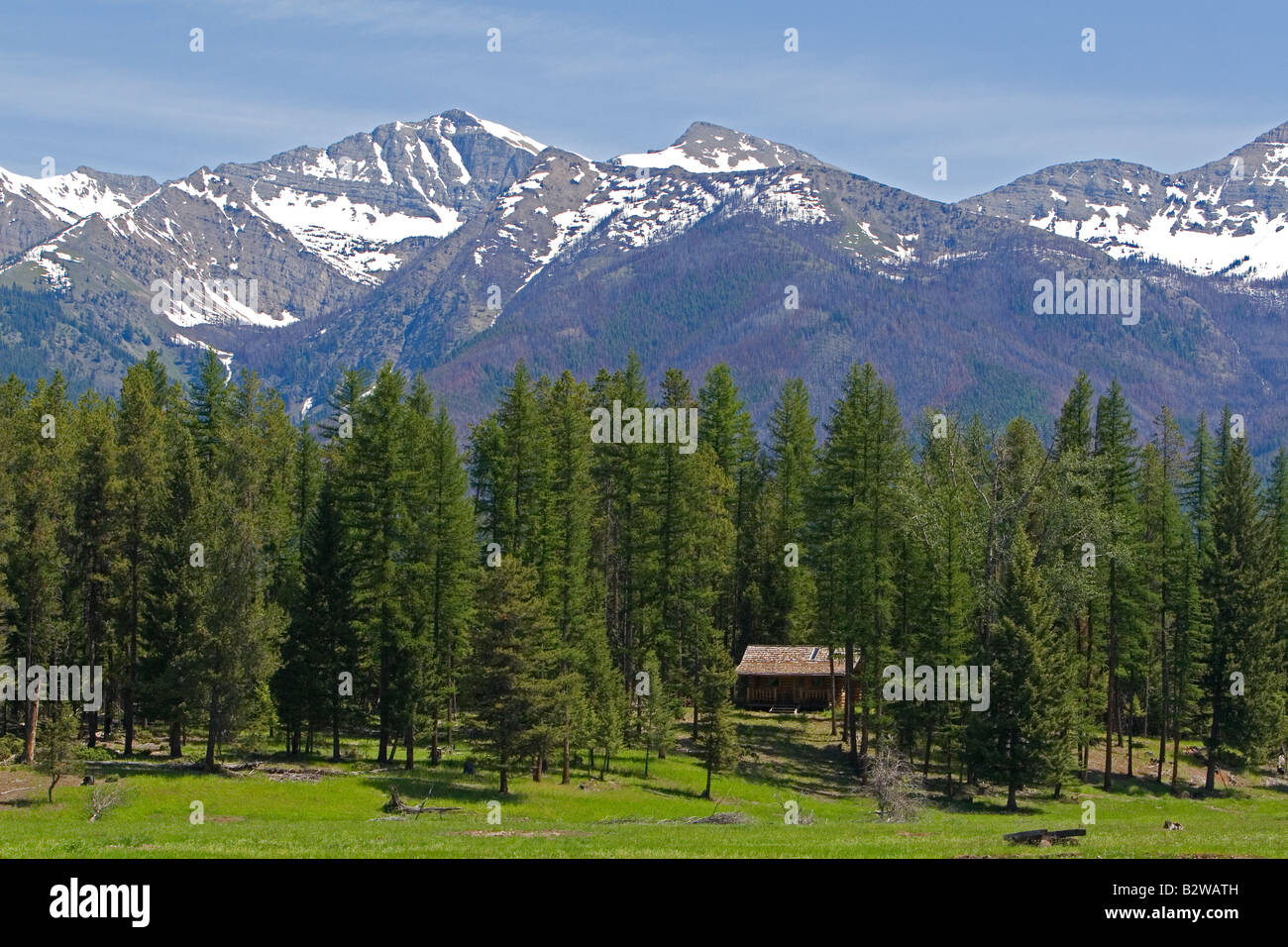Log cabin sits below the Rocky Mountains near Condon Montana Stock Photo