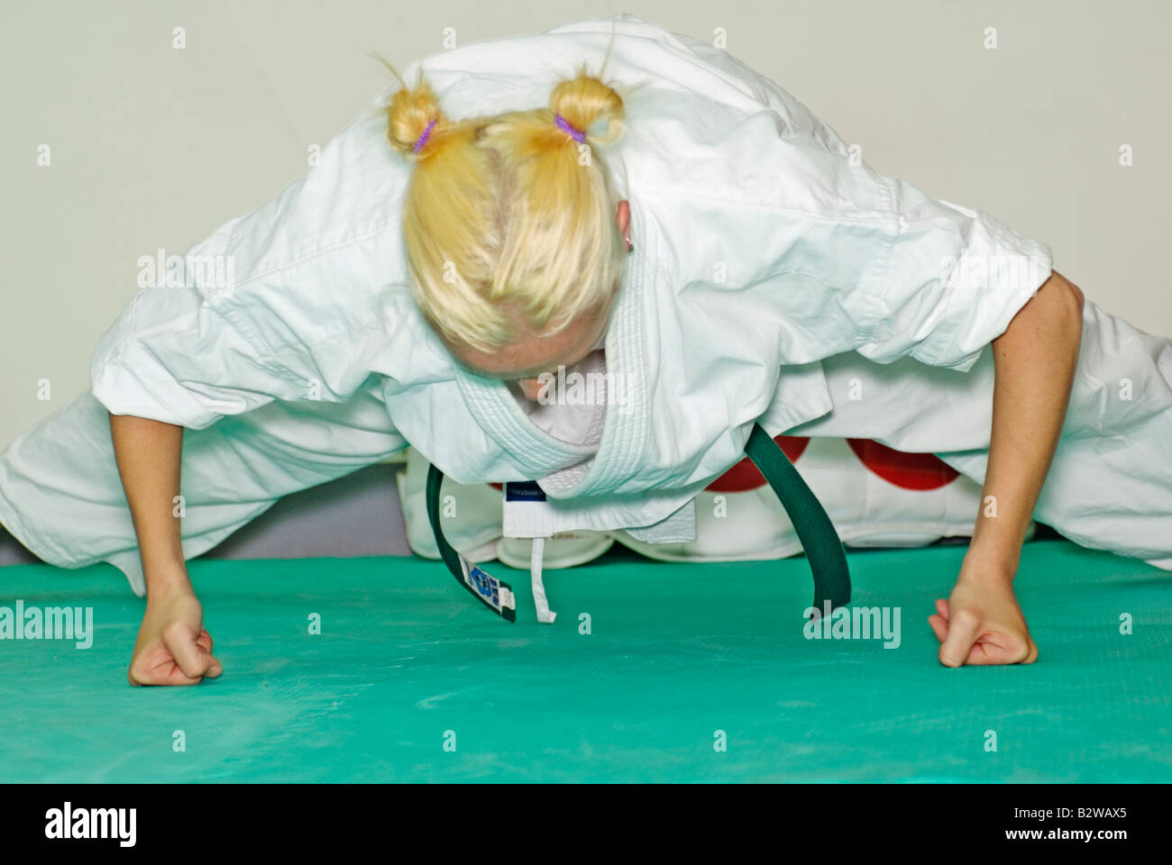 Young woman doing push-ups with clenched fists in karate class Stock Photo