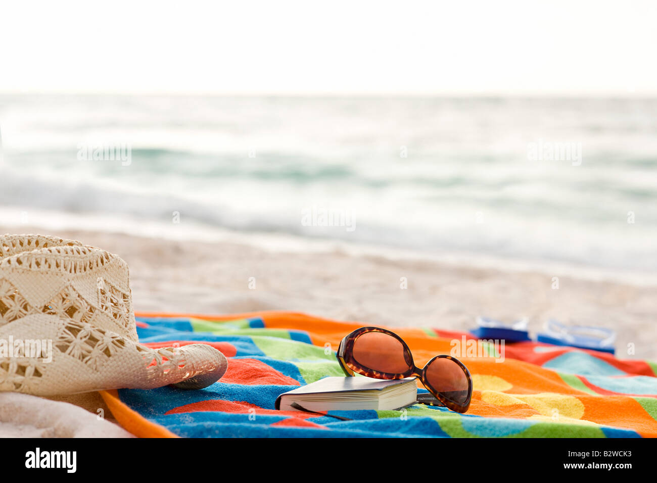 Sun hat sunglasses book and a towel on a beach Stock Photo - Alamy
