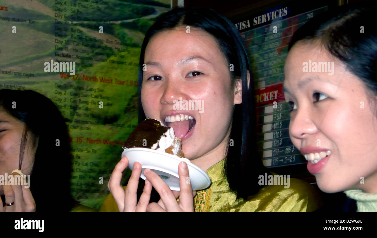 Vietnamese woman scoffs chocolate cream cake Hanoi Vietnam Stock Photo