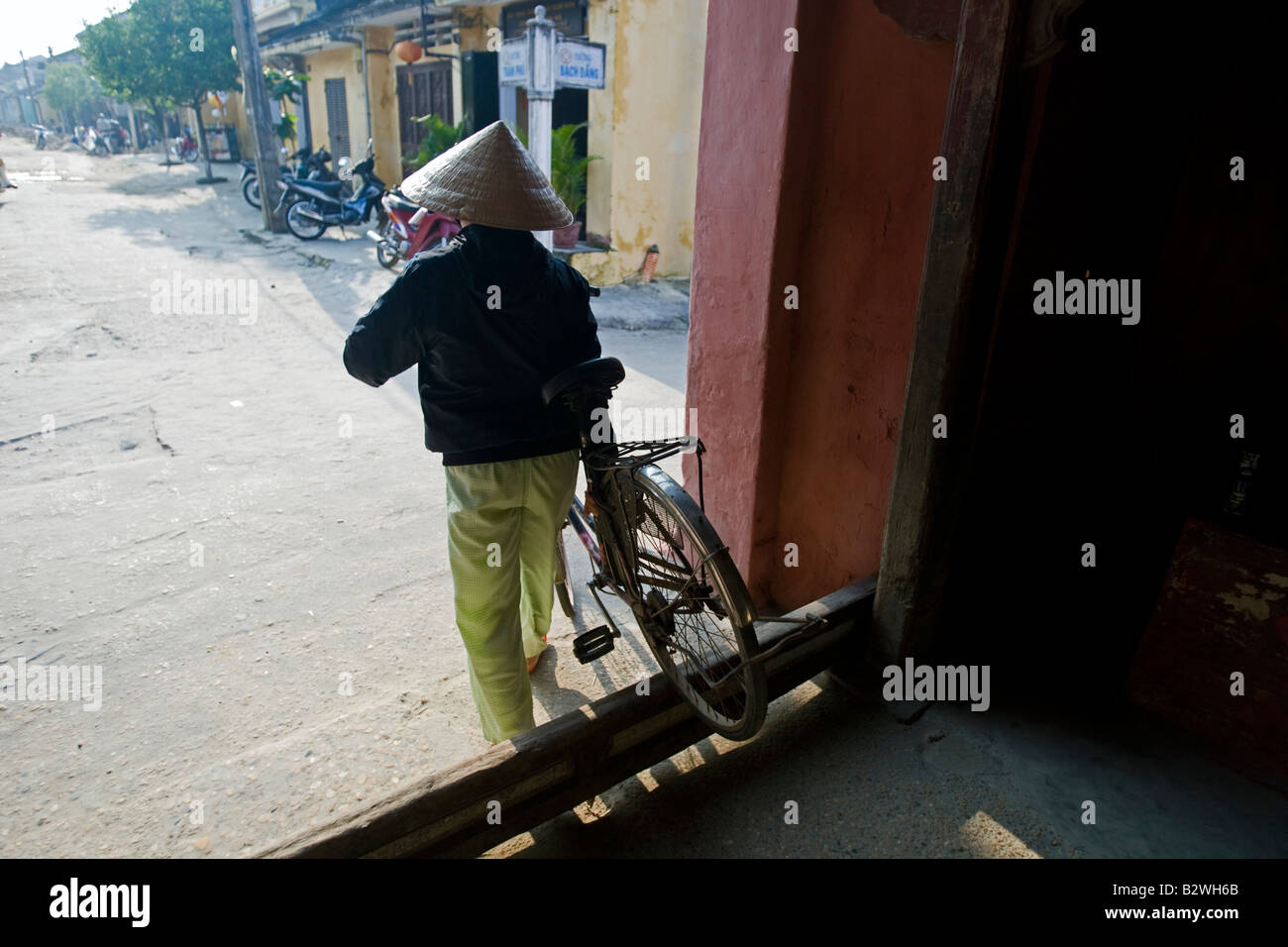 Conical hat woman with bicycle landmark Japanese Covered Bridge Hoi An Vietnam Stock Photo