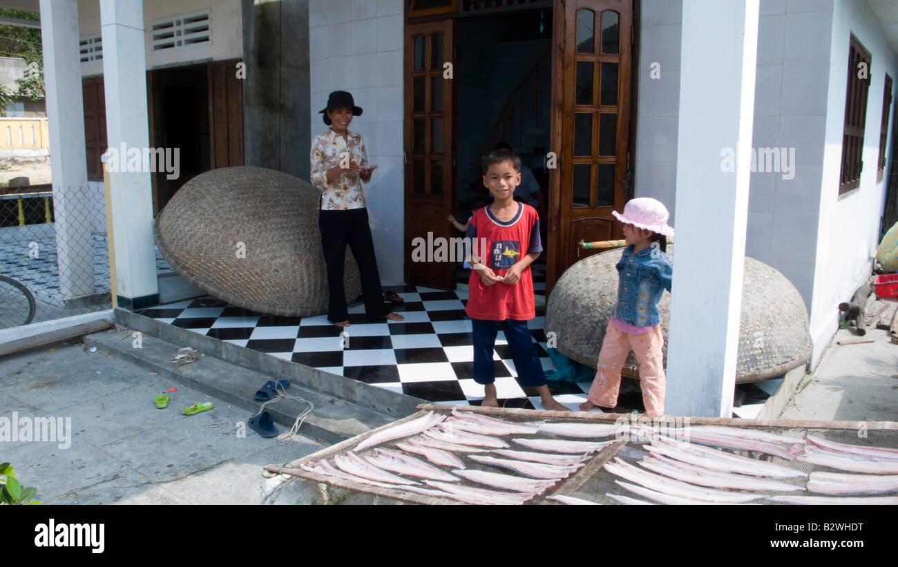 Woman children outside house with fish strips drying on rack Cham Island off historic Hoi An Vietnam Stock Photo