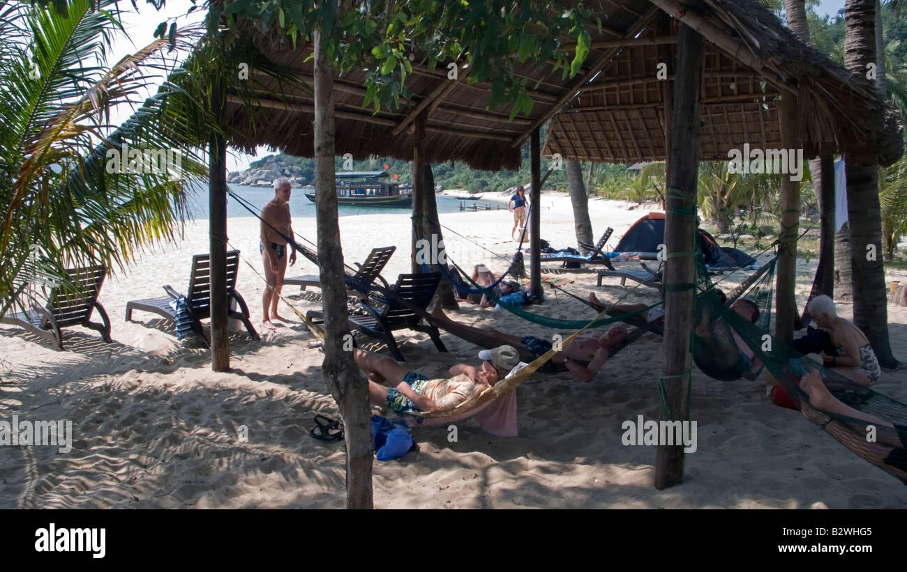 Visitors relax in hammocks on white sand Chong Beach Cham Island off historic Hoi An Vietnam Stock Photo