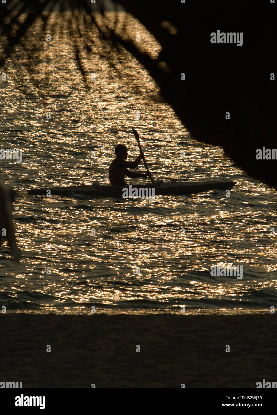 Young man paddles kayak in sunset off Long Beach Phu Quoc Island