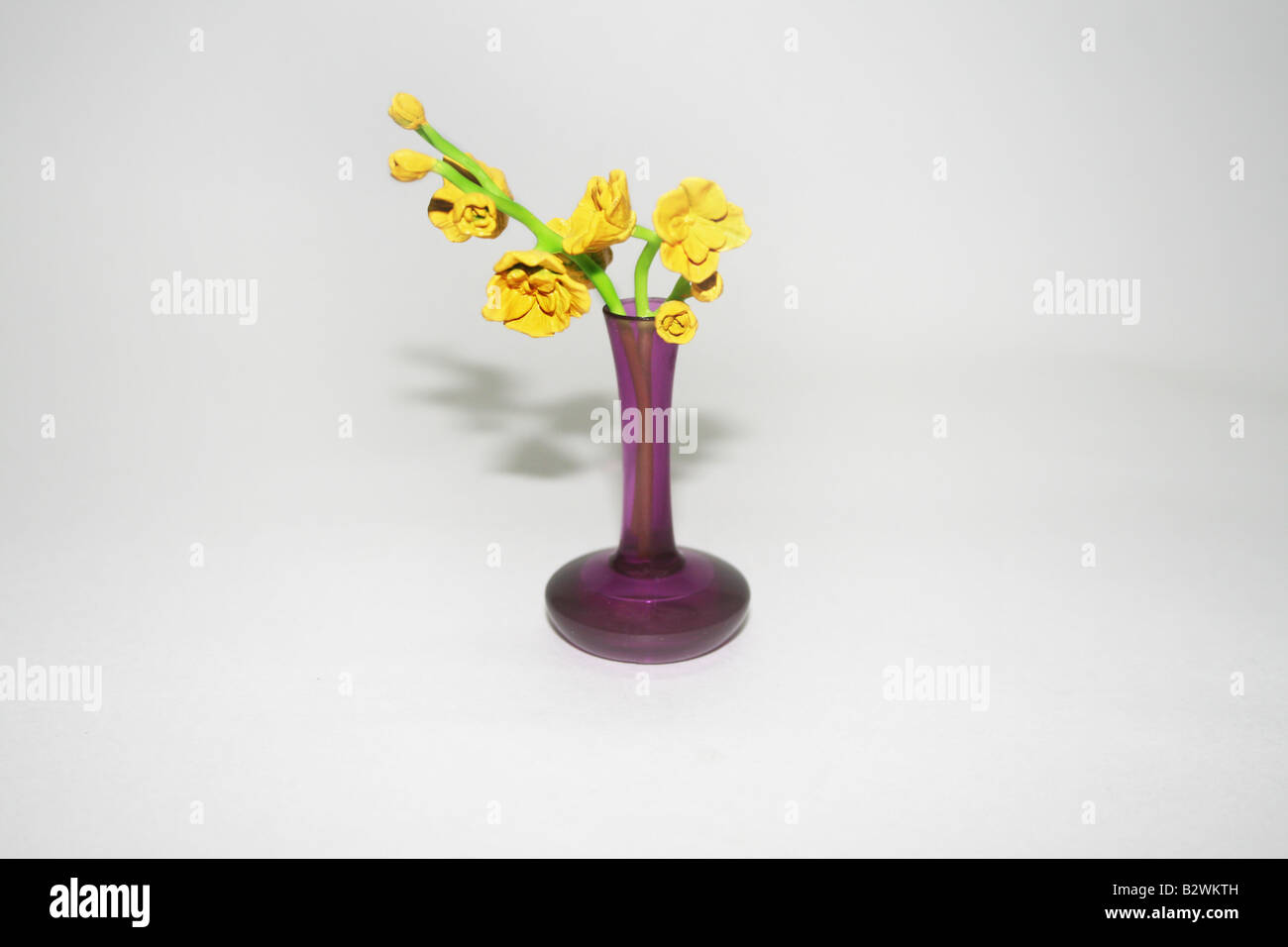 Rare exotic attractive yellow flowers in purple color fancy glass vase of long hollow holder and flat oval shape base Stock Photo