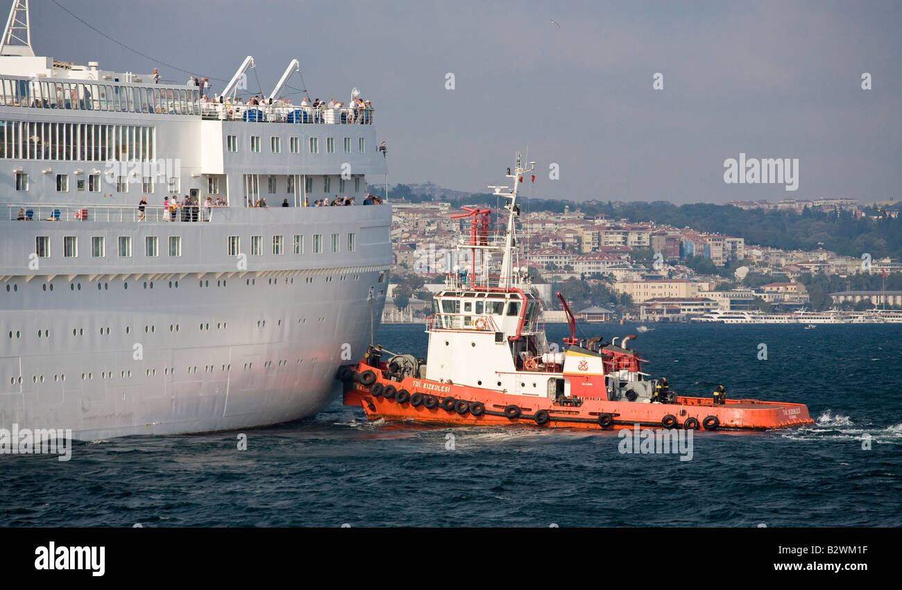 Pushing Around A Bright Orange Tug Pushes At The Stern Of A Large White Cruise Ship To Bring It Into Port Passengers Watch Stock Photo Alamy