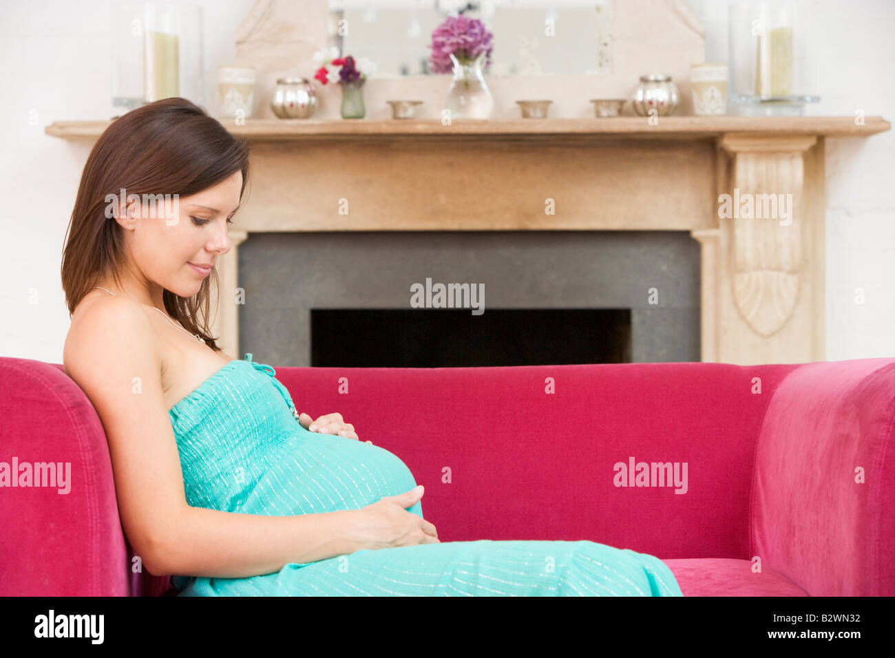 Pregnant woman sitting in living room smiling Stock Photo - Alamy