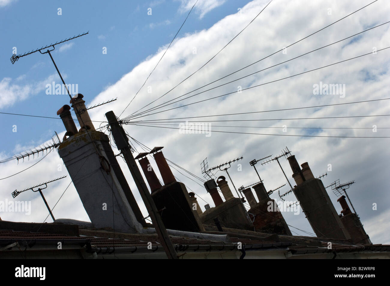 TV aerials and chimneypots on the skyline above a row of terraced houses Stock Photo