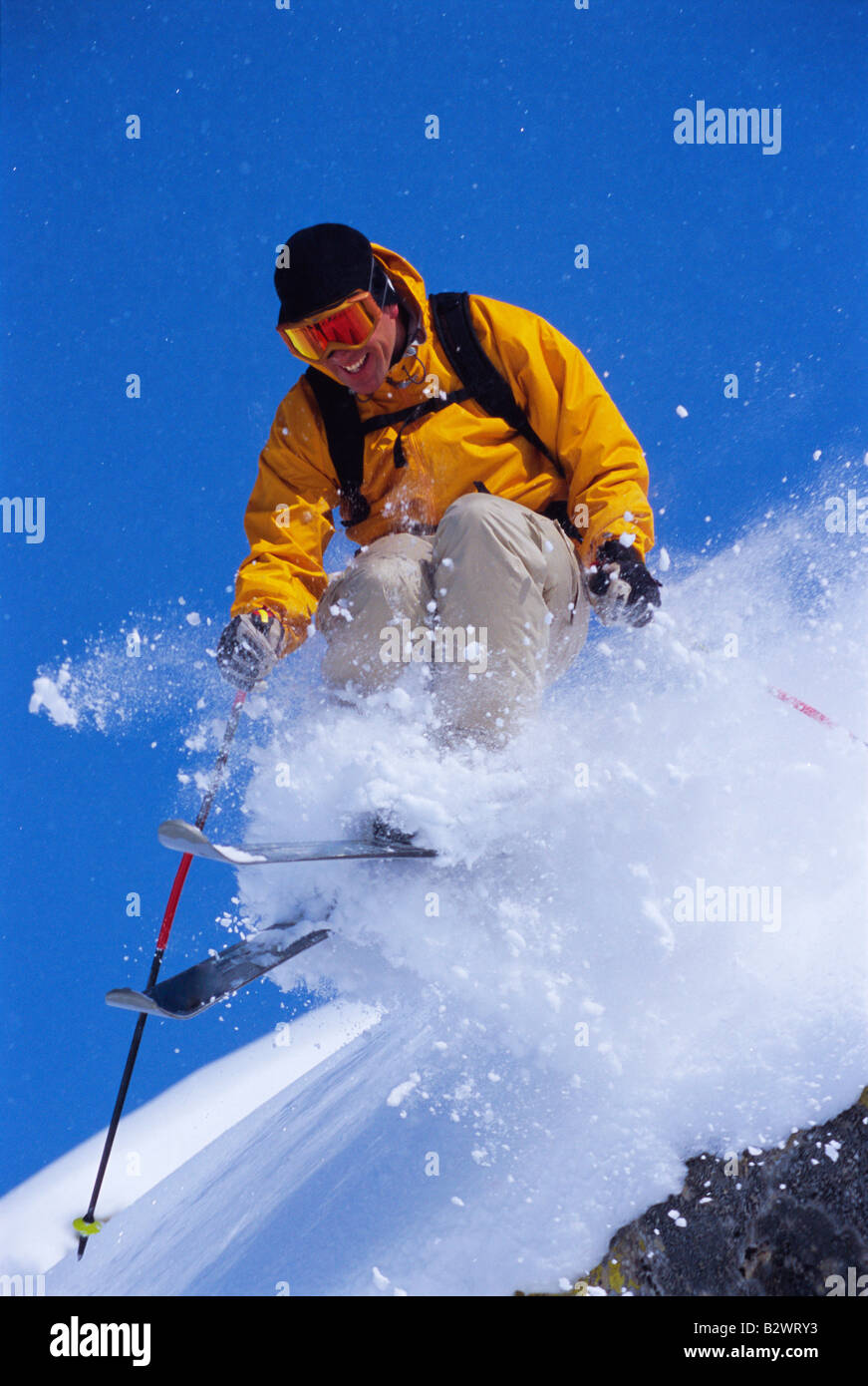 Skier jumping on snowy hill and smiling Stock Photo