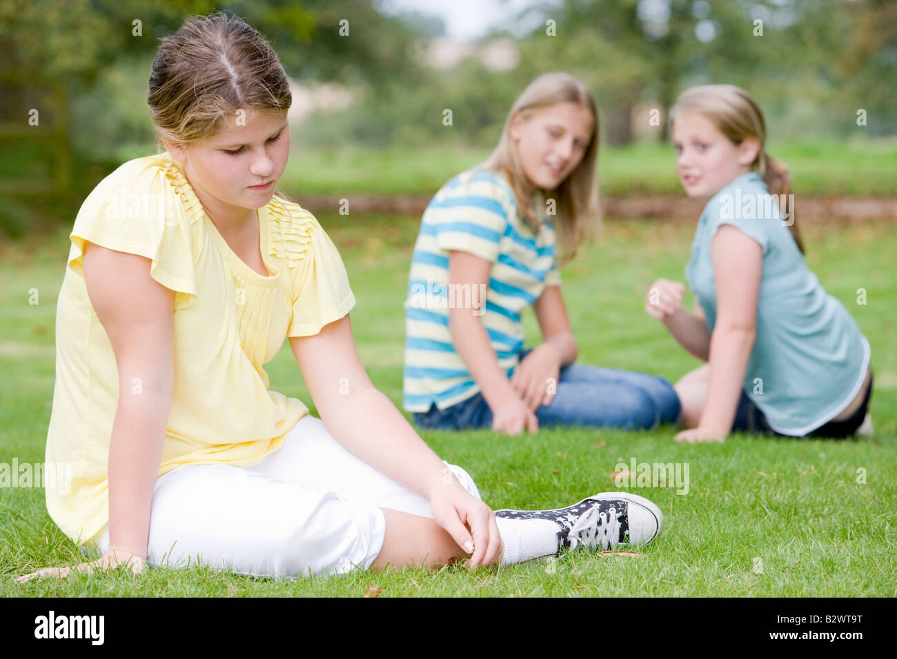 Two young girls bullying other young girl outdoors Stock Photo