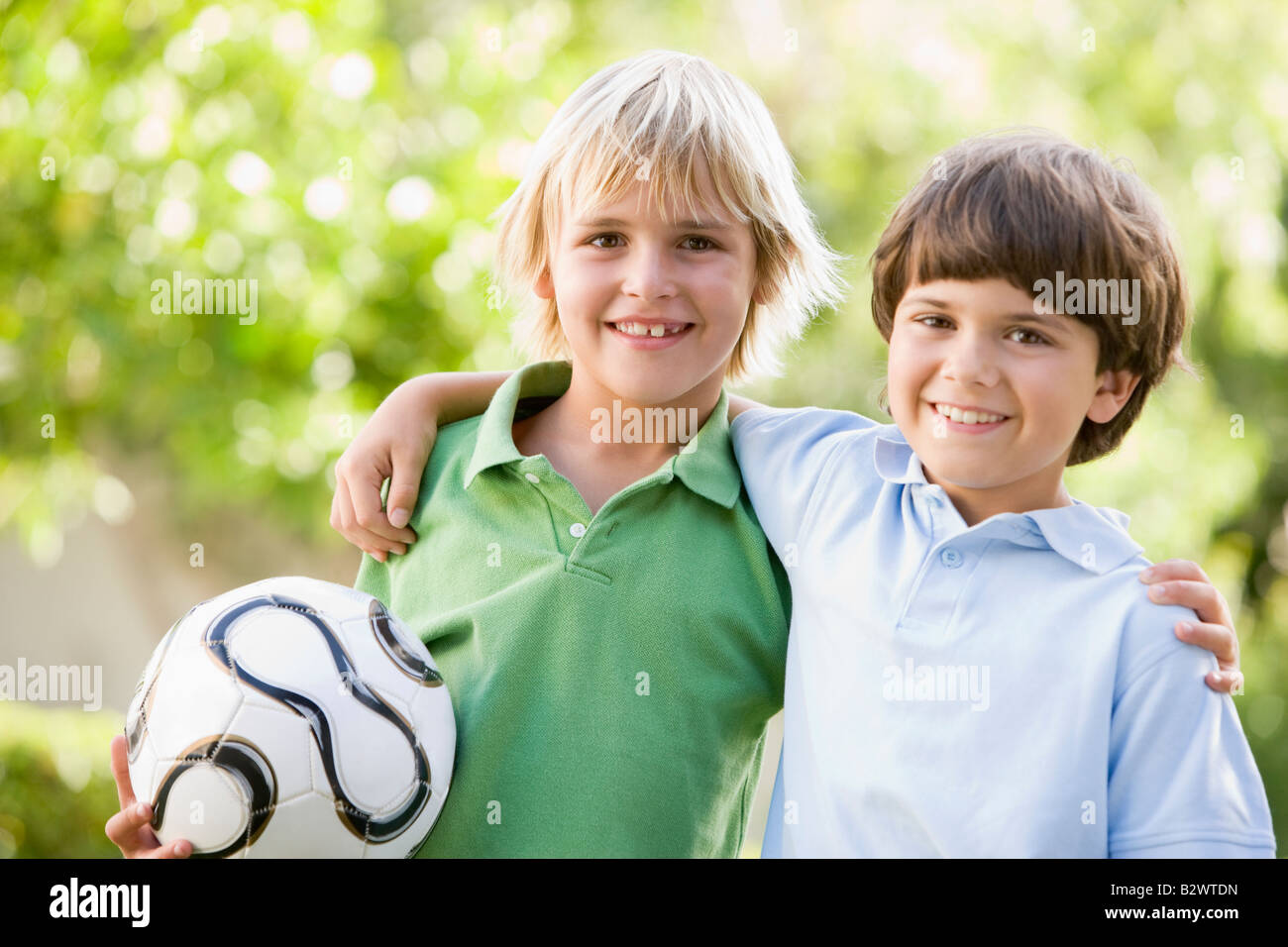 Two young boys outdoors with soccer ball smiling Stock Photo