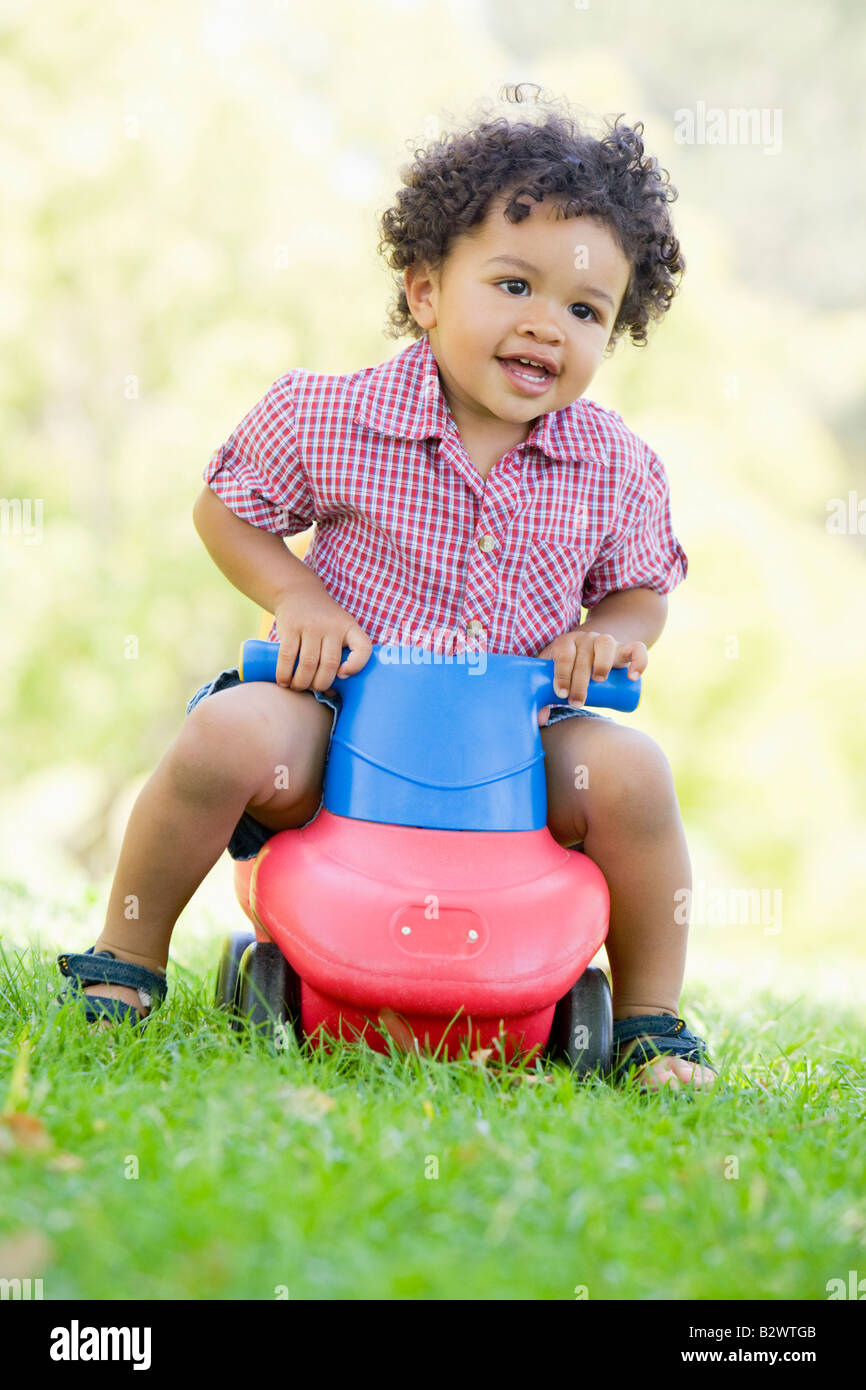 Young boy playing on toy with wheels outdoors Stock Photo Alamy