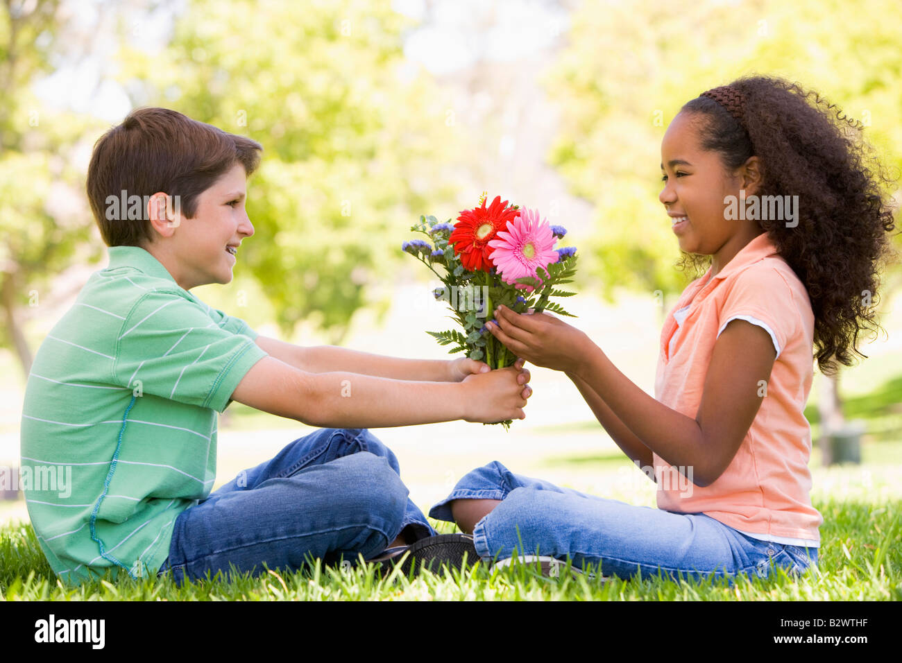 Young boy giving young girl flowers and smiling Stock Photo Alamy