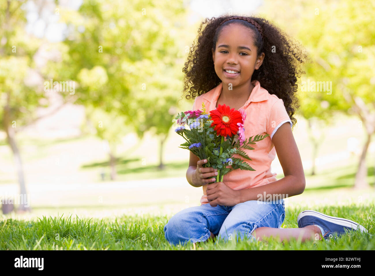Young girl holding flowers and smiling Stock Photo - Alamy