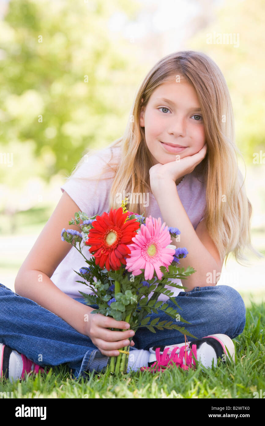 Young girl holding flowers and smiling Stock Photo - Alamy
