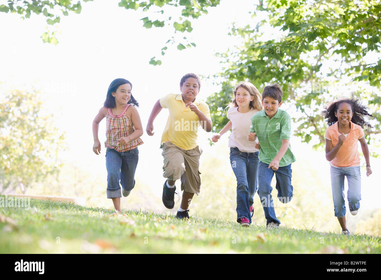 Five young friends running outdoors smiling Stock Photo