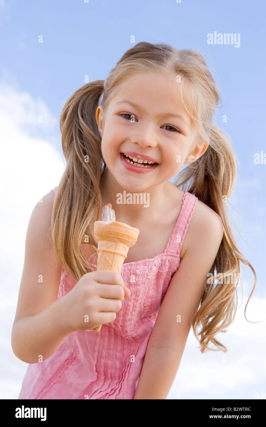 Young girl outdoors eating ice cream cone and smiling Stock Photo Alamy