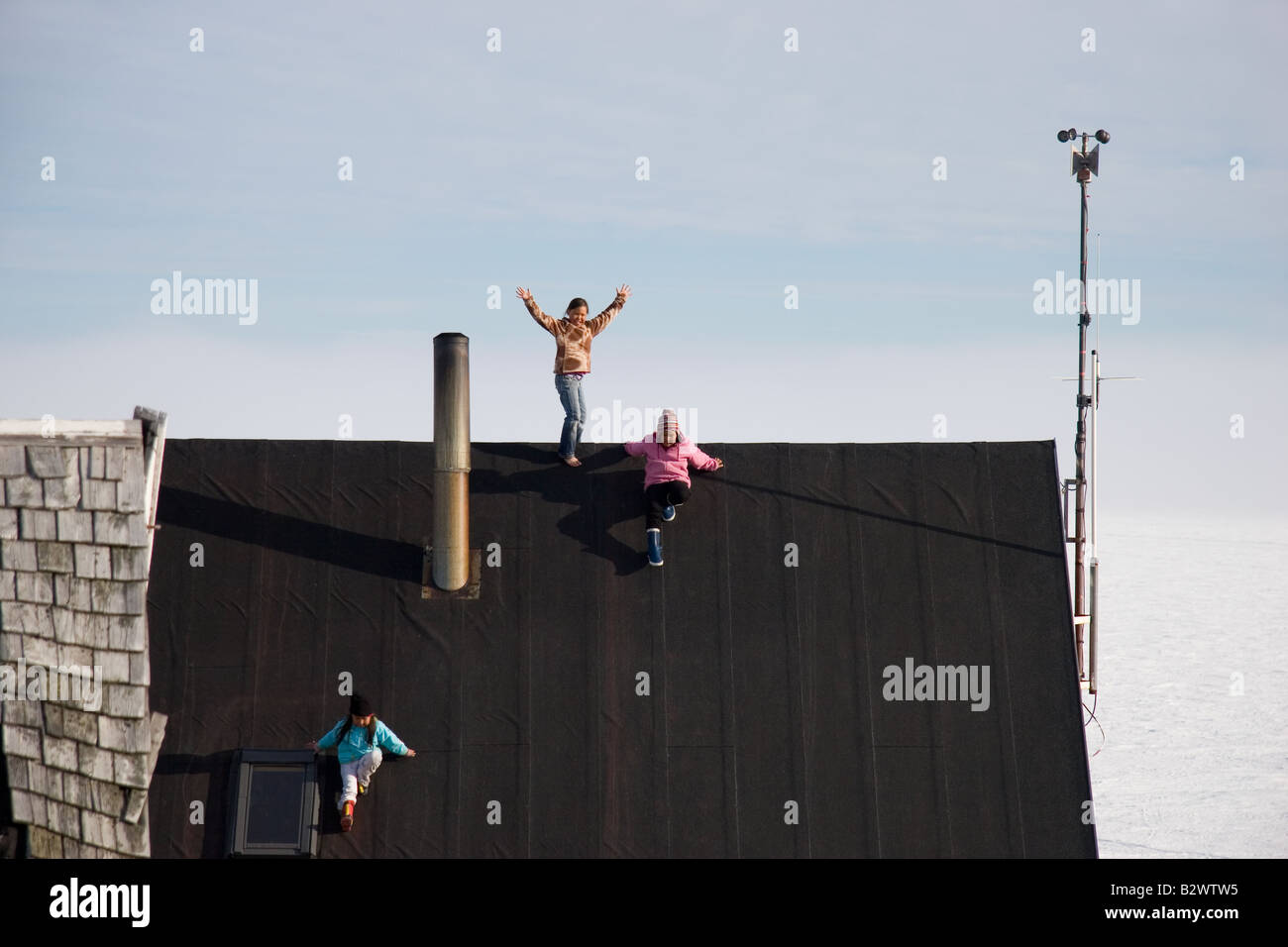 Young Inuit girls play on the post office roof in the village of Ittoqqortoormiit, Scoresbysund, East Greenland Stock Photo