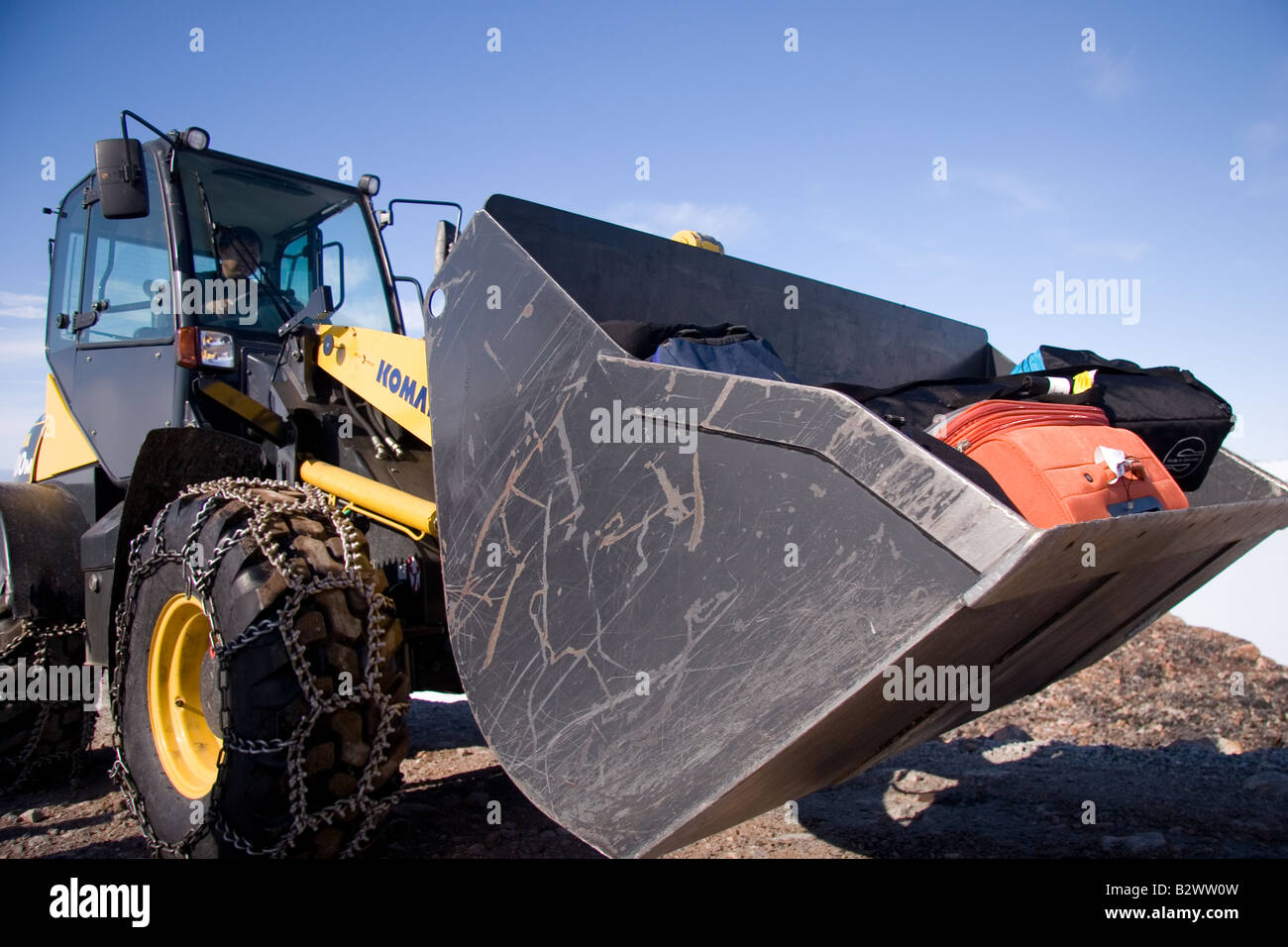 A baggage handler transports suitcases by tractor in the village of Ittoqqortoormiit, Scoresbysund, East Greenland Stock Photo