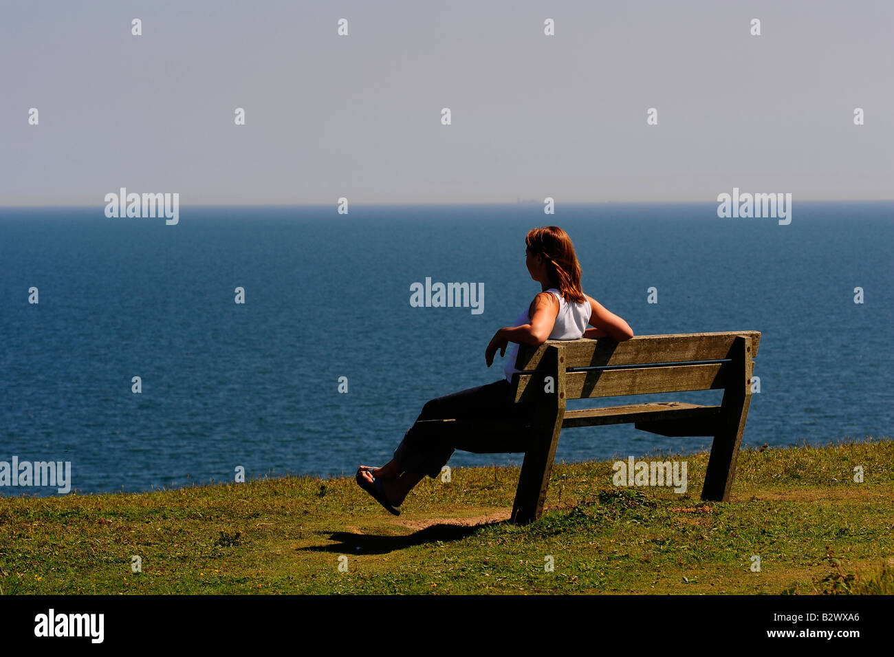 A woman sitting looking out to sea Stock Photo - Alamy