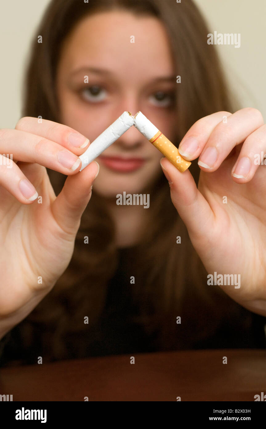 An adolescent caucasian girl breaking a cigarette in half. Shot with minimum depth of field Focus is on the cigarette. Stock Photo