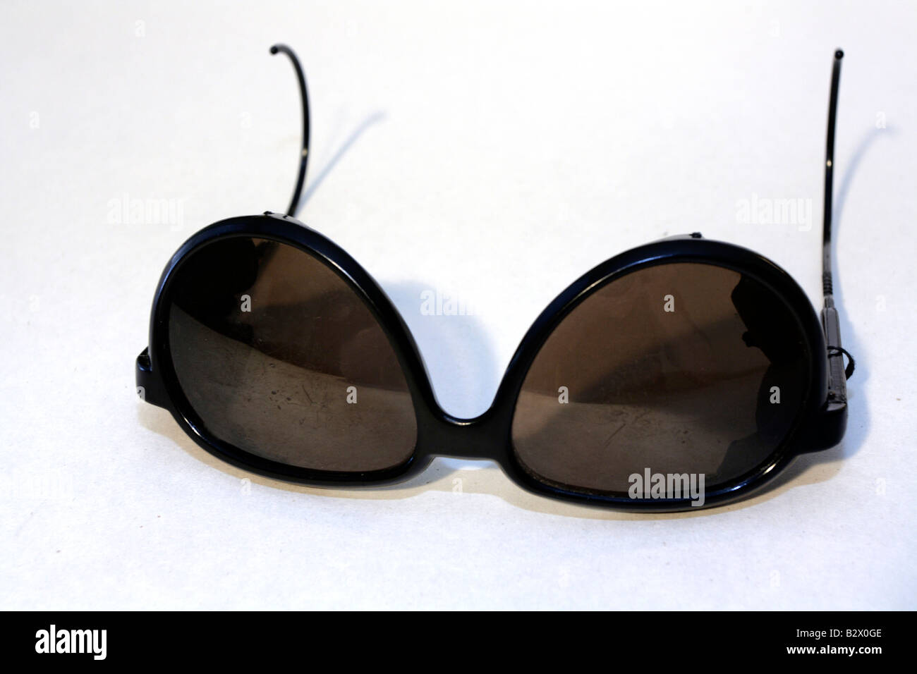 Scratched and distressed sunglasses laying upside down on white. Stock Photo