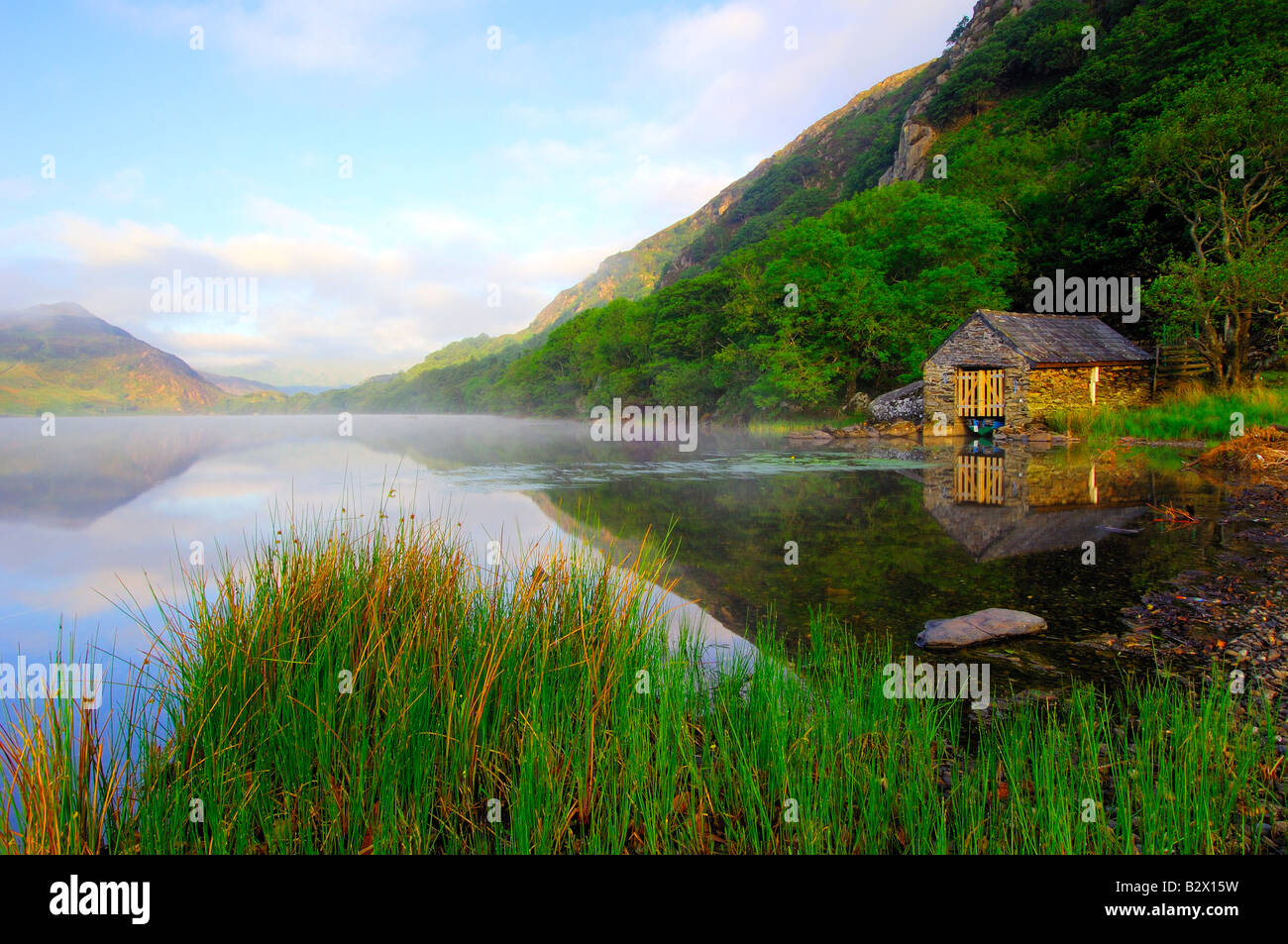 A small boathouse on a beautifully calm and misty morning at Llyn Dinas in Snowdonia national park North Wales Stock Photo
