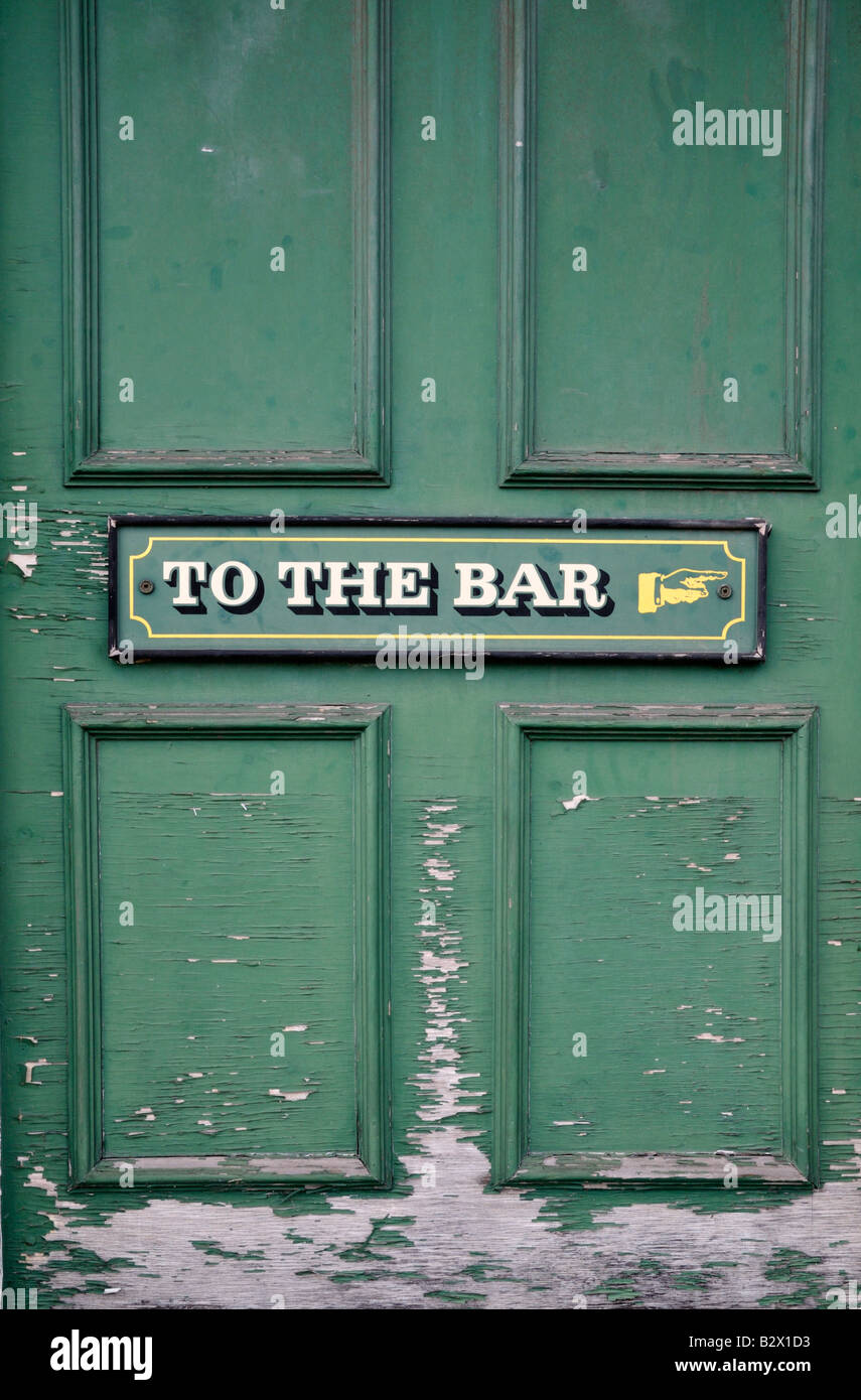 Pub door showing weathered sign 'To the bar' with a painted hand pointing to the right 2/2 Stock Photo