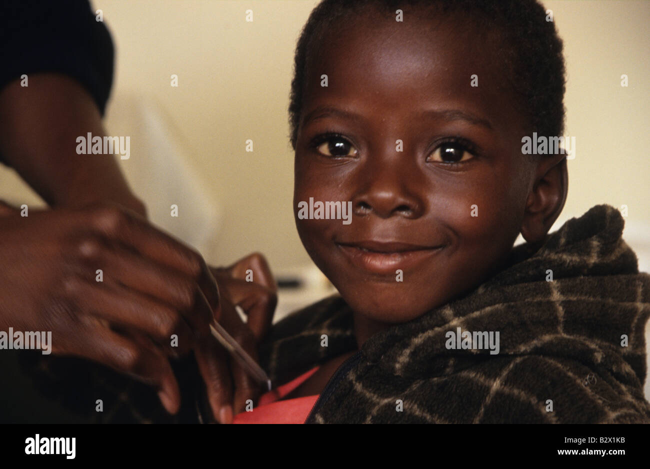 An young orphan has his temperature taken by a nurse at the orphanage, Zimbabwe, Africa Stock Photo