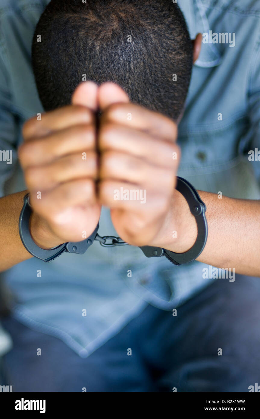 A young black male in handcuffs. Shot with minimum depth of field Focus is on the cuffs. Stock Photo