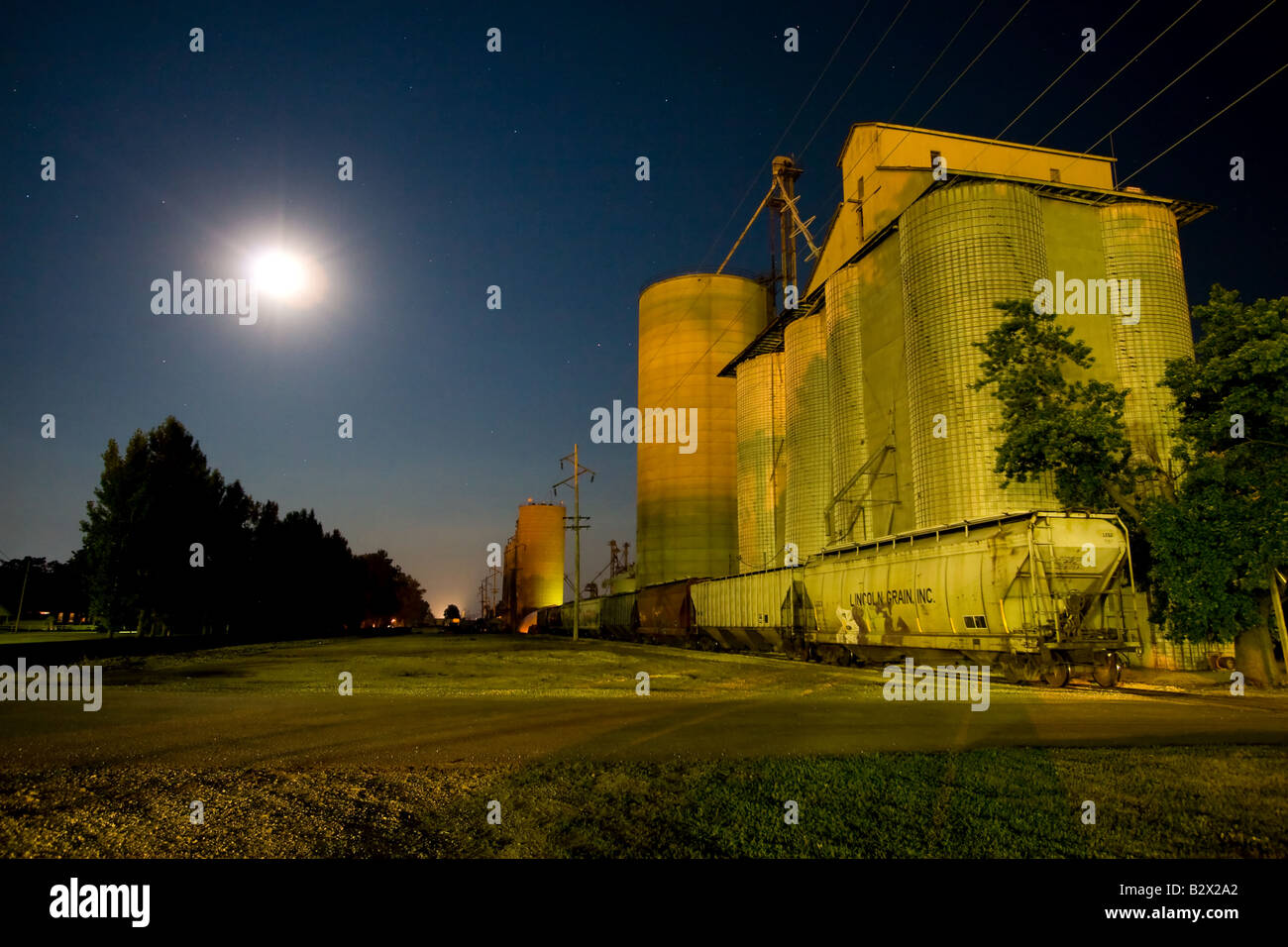 The large elevator at Clifton, IL is preparing to load railroad cars with grain under a full moon. Stock Photo