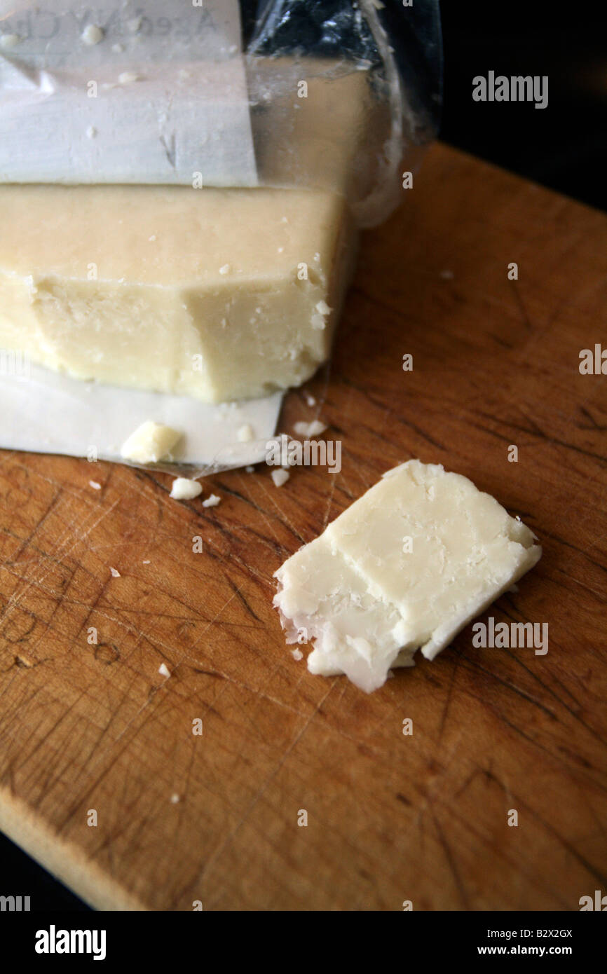 Artisan white cheddar cheese in wrapper on wood board. Stock Photo