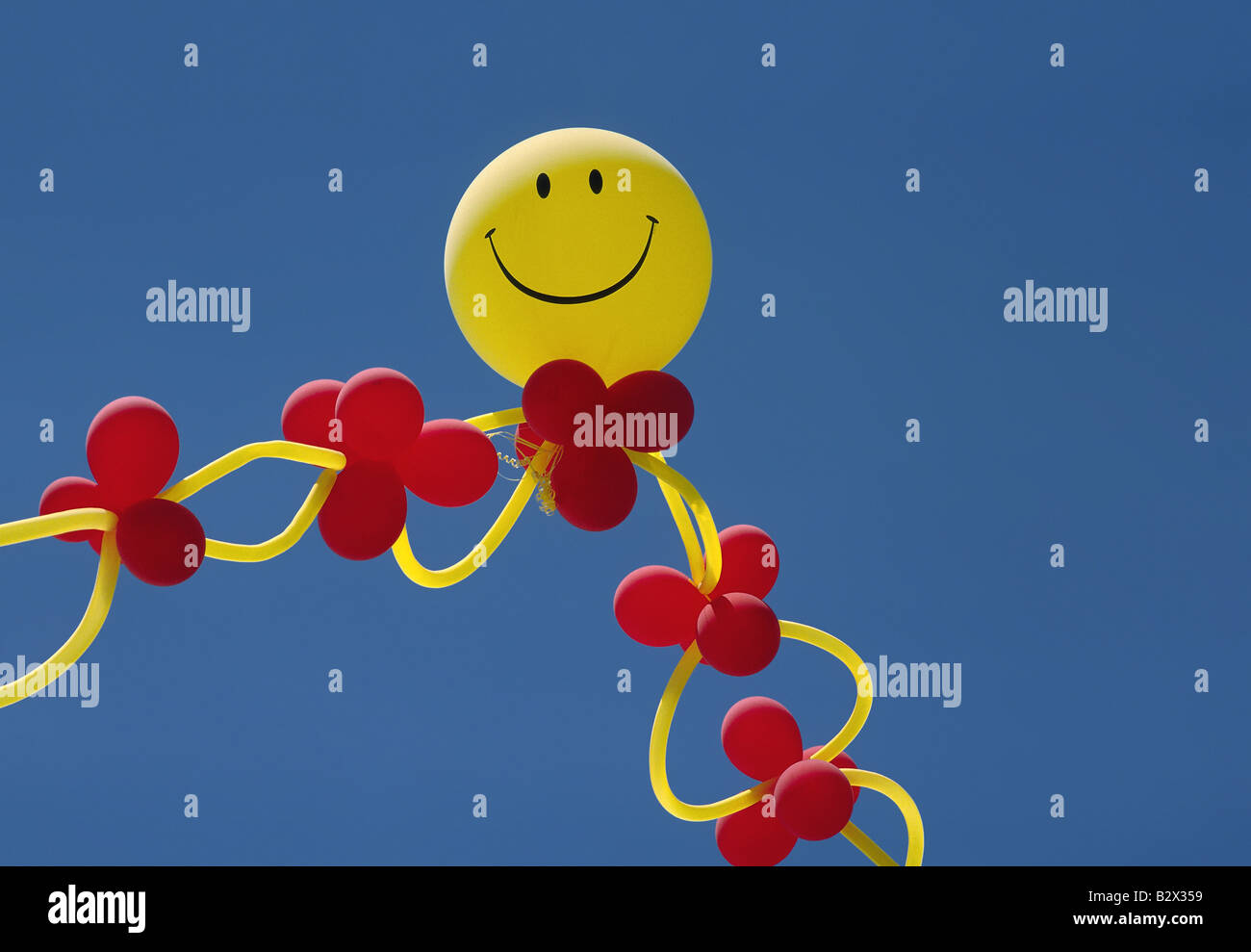 Colorful balloon arrangement topped with yellow Smiley Face balloon Stock Photo