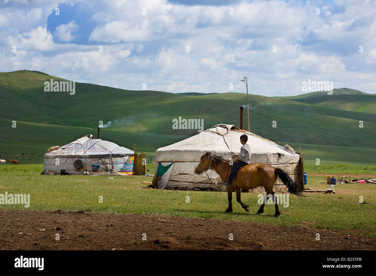 Young boy riding a horse in front of his nomadic family's ger tent ...