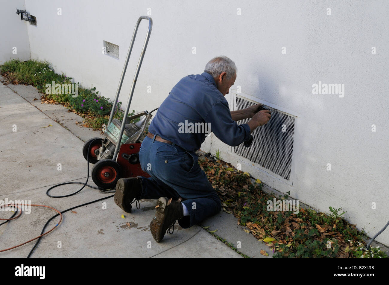 Plumber opening entrance to inspect pipes under house Stock Photo