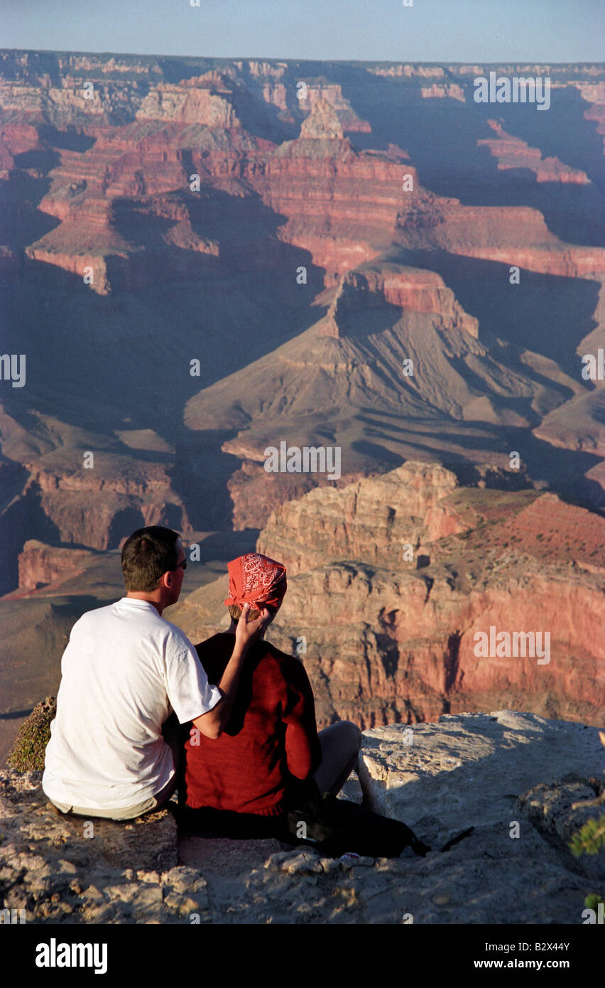 A man and a woman sit together at the edge of the Grand Canyon at ...
