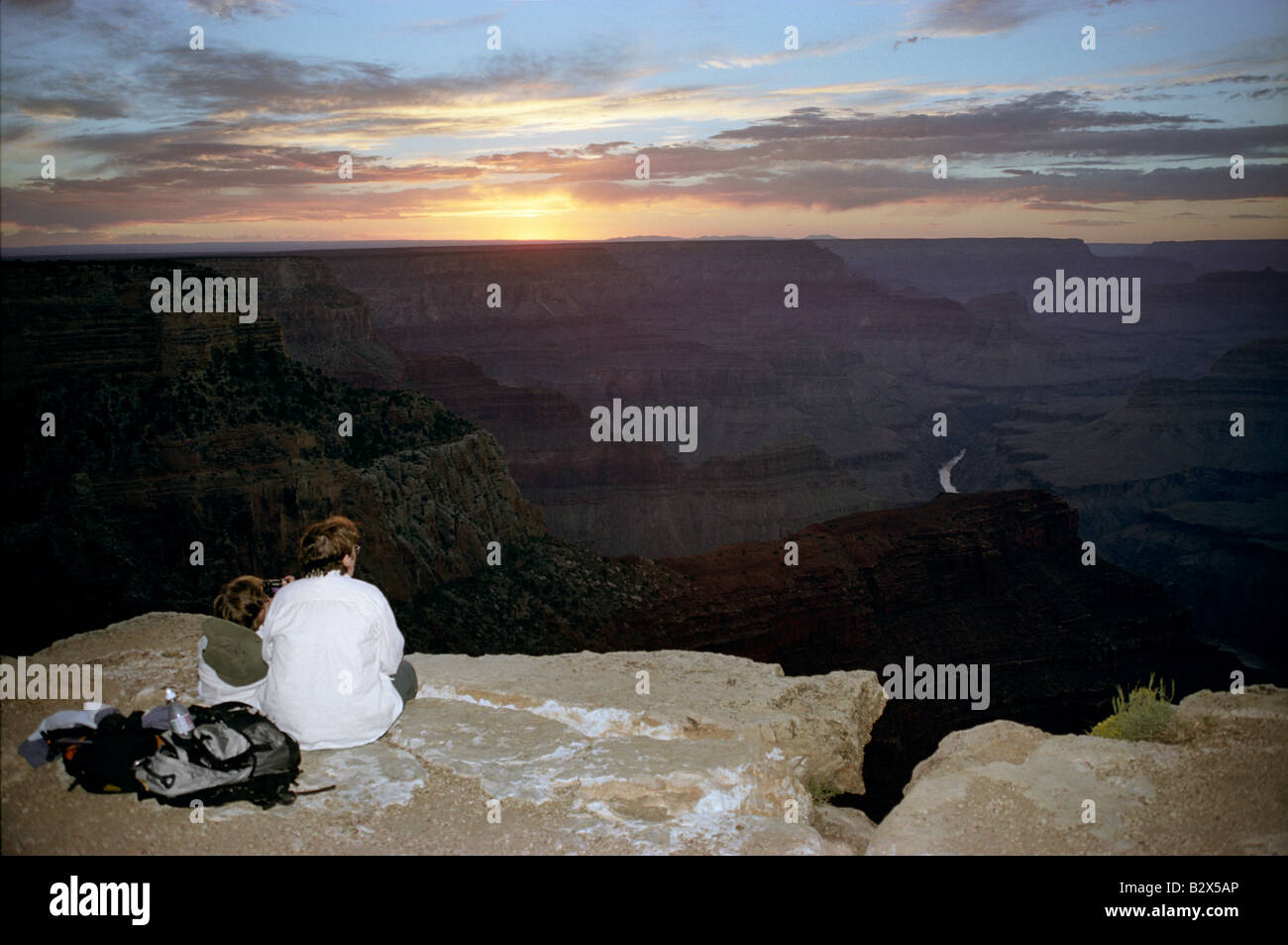 A woman and a child sit at the edge of the Grand Canyon at Grand Canyon ...