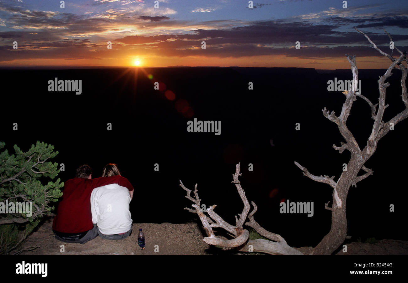 A man and a woman sit together at the edge of the Grand Canyon at ...